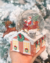 Load image into Gallery viewer, Musical Snow Globe. Plays Jingle Bells. beautiful snow globe. Santa in his sleigh upon the rooftop, with his reindeers leaping off the roof. Dimensions: 6.5&quot;H 7.25&quot;W 4.375&quot;L
